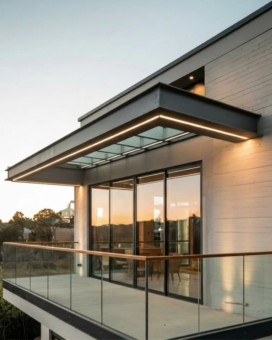 Modern home with frameless glass balcony railing and slim aluminium sliding doors at sunset
